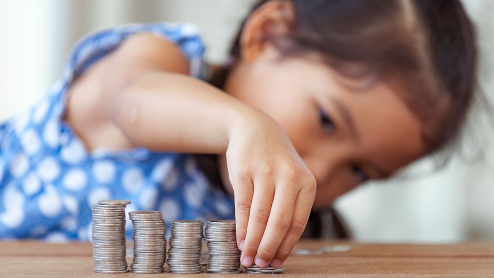 asian little girl playing with coins making stacks of money